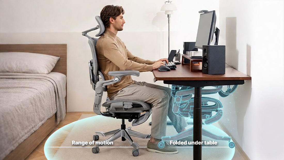 Man working at a standing desk in a grey Hinomi ergonomic chair in a compact bedroom home office